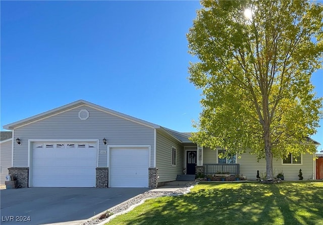 single story home with a porch, a front yard, driveway, and an attached garage