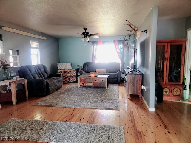 living room with a ceiling fan, a wealth of natural light, a textured ceiling, and hardwood / wood-style flooring