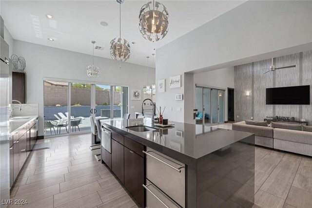 kitchen with sink, hanging light fixtures, a center island with sink, and dark brown cabinetry