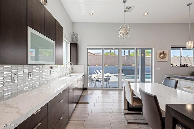 kitchen with sink, decorative light fixtures, decorative backsplash, and a healthy amount of sunlight