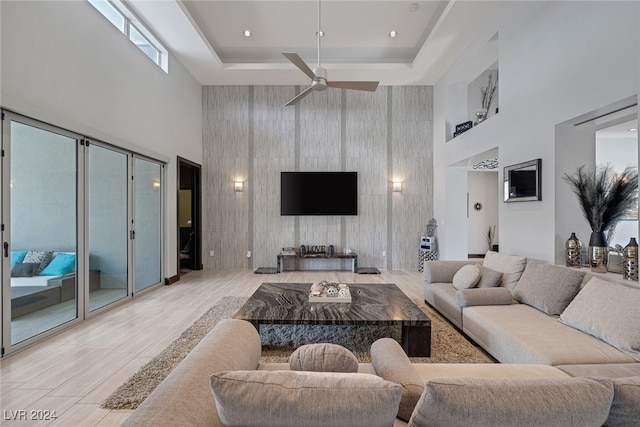 living room featuring ceiling fan, a high ceiling, and a tray ceiling