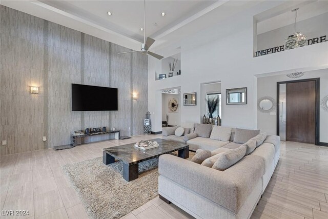 living room featuring ceiling fan, light tile patterned floors, and a high ceiling