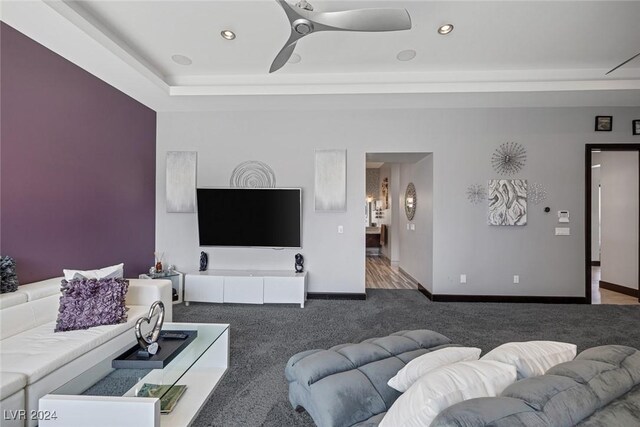 living room with ceiling fan, carpet, and a raised ceiling