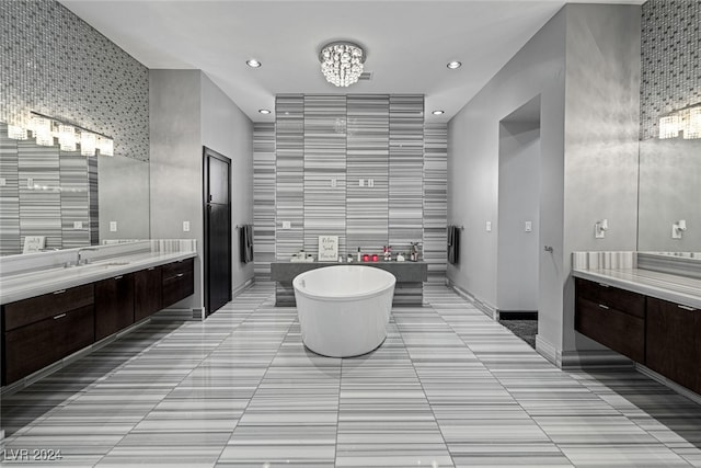 bathroom featuring vanity, tile patterned floors, tile walls, a bath, and an inviting chandelier