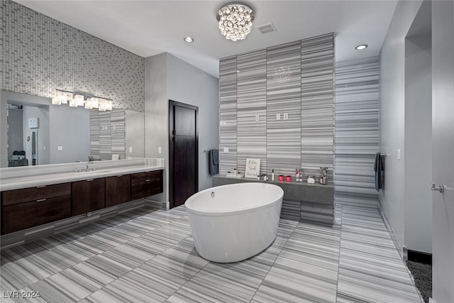 bathroom featuring tile walls, tile patterned floors, vanity, and a bath