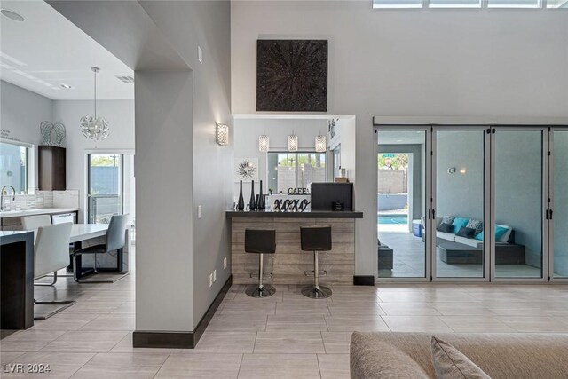 interior space with a wealth of natural light, a high ceiling, light tile patterned floors, and a chandelier