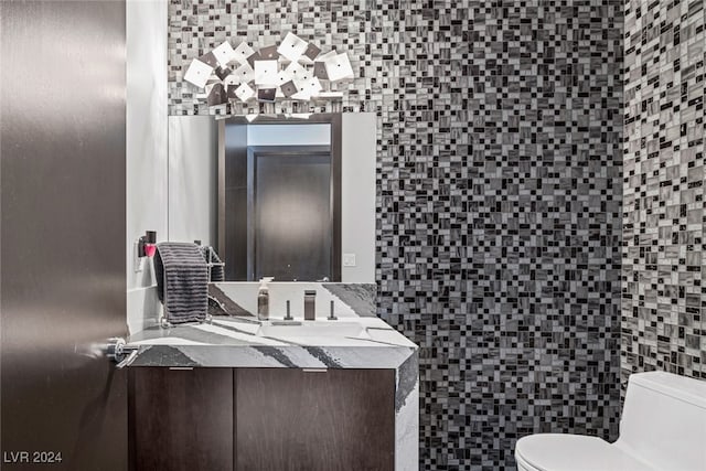 bathroom with toilet, vanity, and tile walls