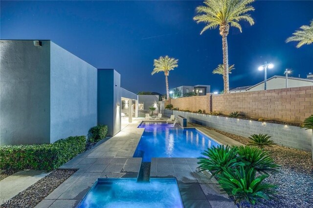 pool at twilight featuring a patio and pool water feature