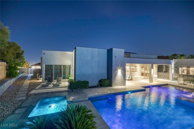 back house at twilight featuring a patio and a fenced in pool