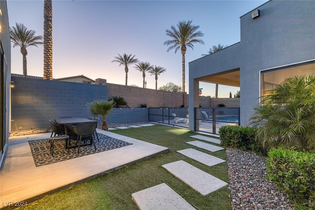 yard at dusk featuring a patio area and a fenced in pool