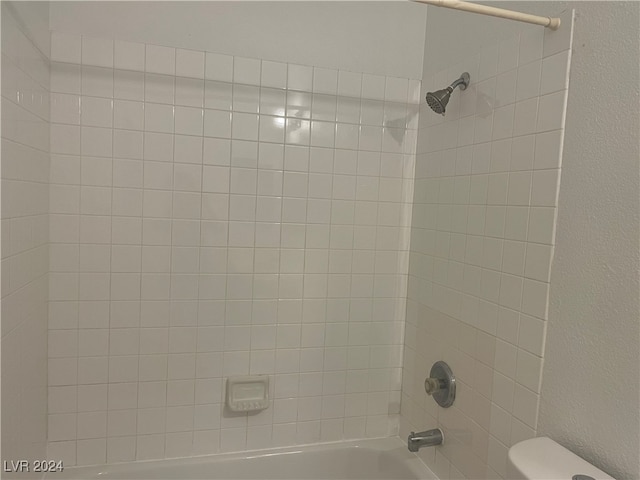 interior space featuring tiled shower / bath and toilet