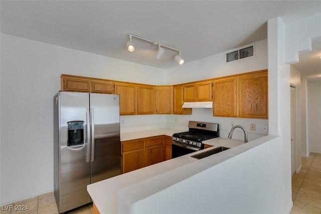 kitchen with appliances with stainless steel finishes, kitchen peninsula, sink, and light tile patterned floors