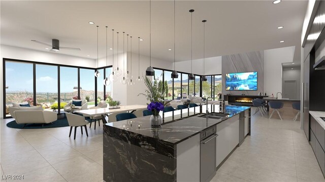 kitchen featuring decorative light fixtures, a large island, sink, ceiling fan, and dark stone countertops