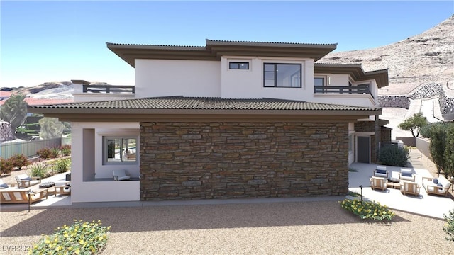 rear view of house featuring stone siding, a patio, a tile roof, and stucco siding