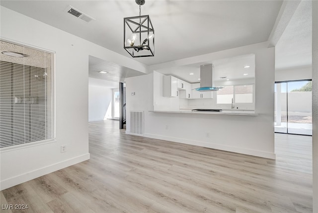 unfurnished living room featuring light wood-type flooring and an inviting chandelier