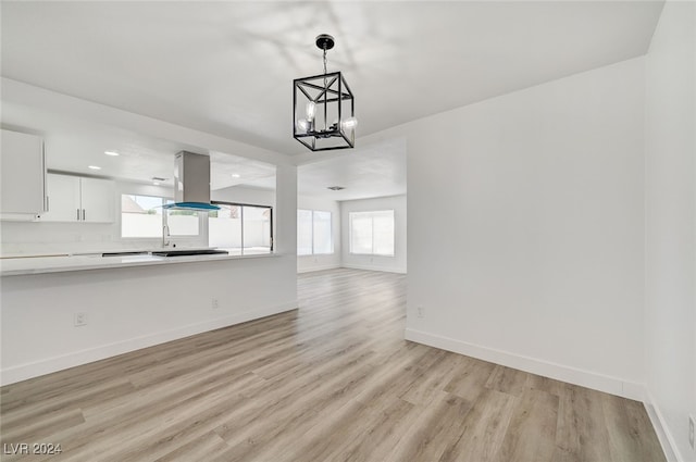 unfurnished living room with light hardwood / wood-style floors, an inviting chandelier, and plenty of natural light