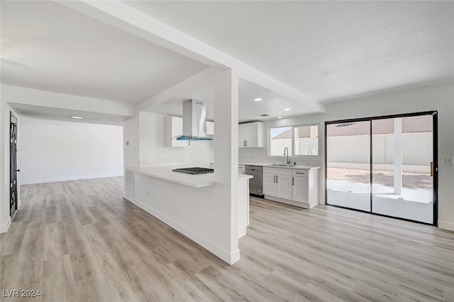 kitchen featuring wall chimney range hood, light wood-type flooring, white cabinetry, and appliances with stainless steel finishes