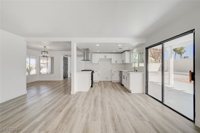 interior space with light hardwood / wood-style floors, range, wall chimney exhaust hood, and white cabinetry