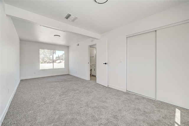 unfurnished bedroom with a closet and light carpet