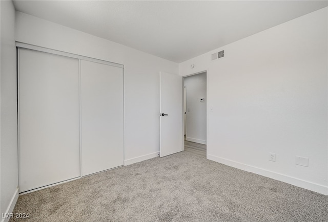 unfurnished bedroom with light colored carpet and a closet