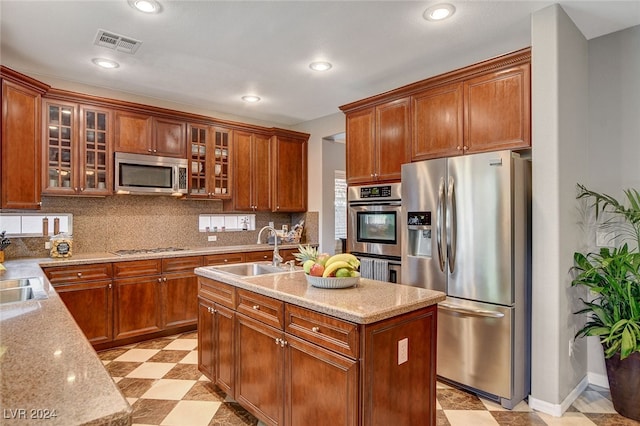 kitchen featuring sink, decorative backsplash, a kitchen island with sink, light tile patterned floors, and stainless steel appliances