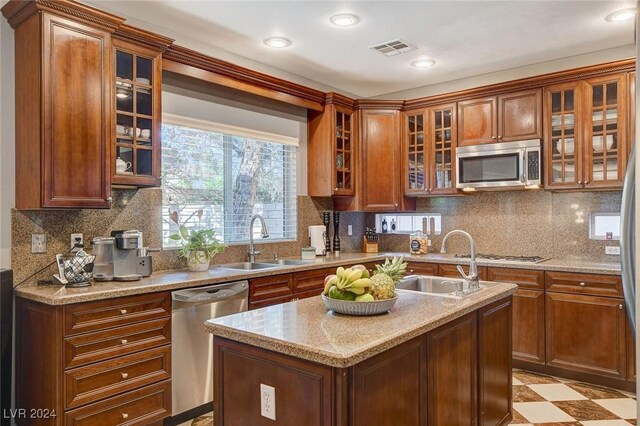 kitchen featuring sink, a kitchen island with sink, backsplash, and stainless steel appliances