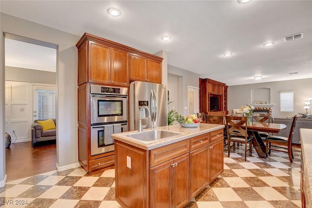 kitchen with sink, light tile patterned floors, a center island with sink, and stainless steel appliances