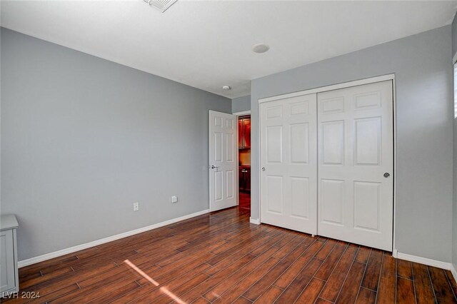 unfurnished bedroom featuring a closet and dark hardwood / wood-style flooring