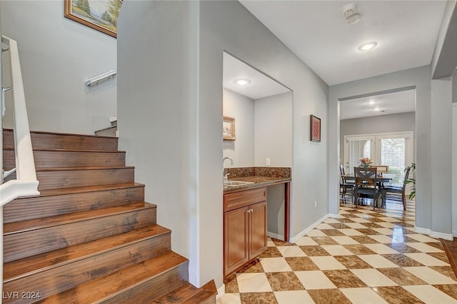 interior space featuring light tile patterned flooring, sink, and dark stone counters