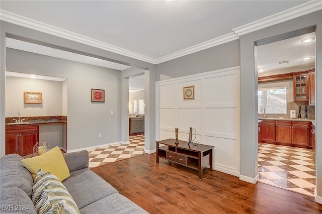 tiled living room with sink and ornamental molding