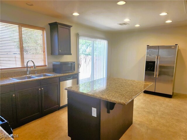 kitchen featuring light stone counters, light tile patterned floors, sink, a center island, and stainless steel appliances