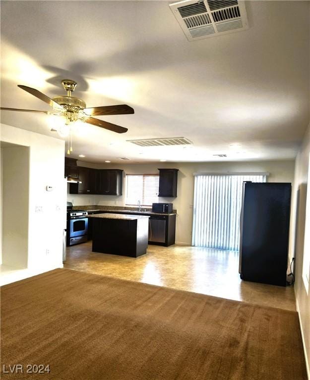 kitchen with gas range, a kitchen island, visible vents, and open floor plan