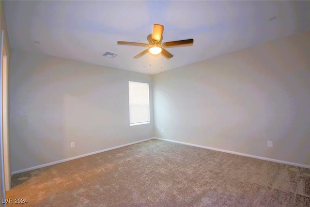 carpeted spare room with ceiling fan, visible vents, and baseboards