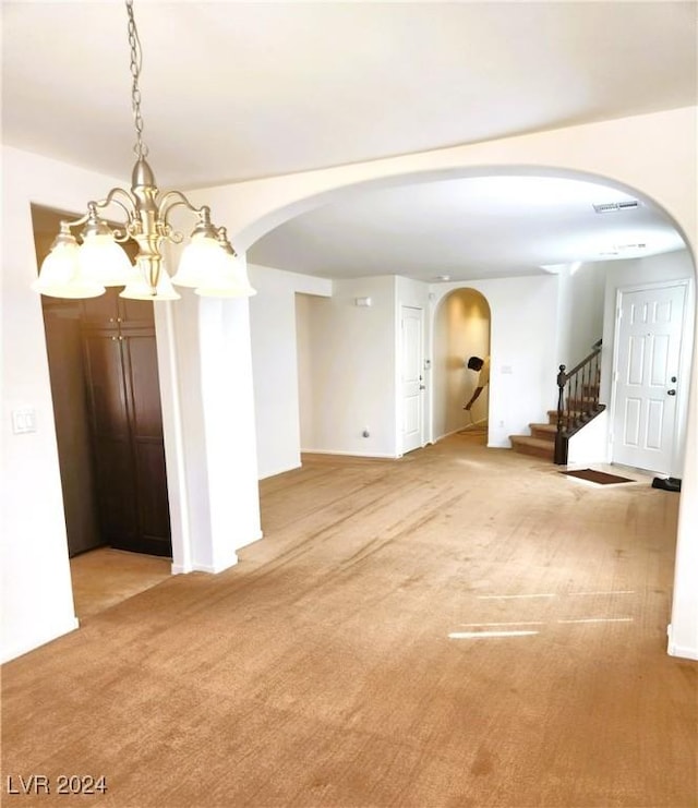 spare room featuring arched walkways, stairway, carpet, and visible vents