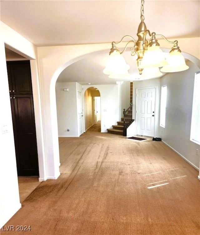 unfurnished dining area featuring baseboards, stairs, arched walkways, and carpet flooring