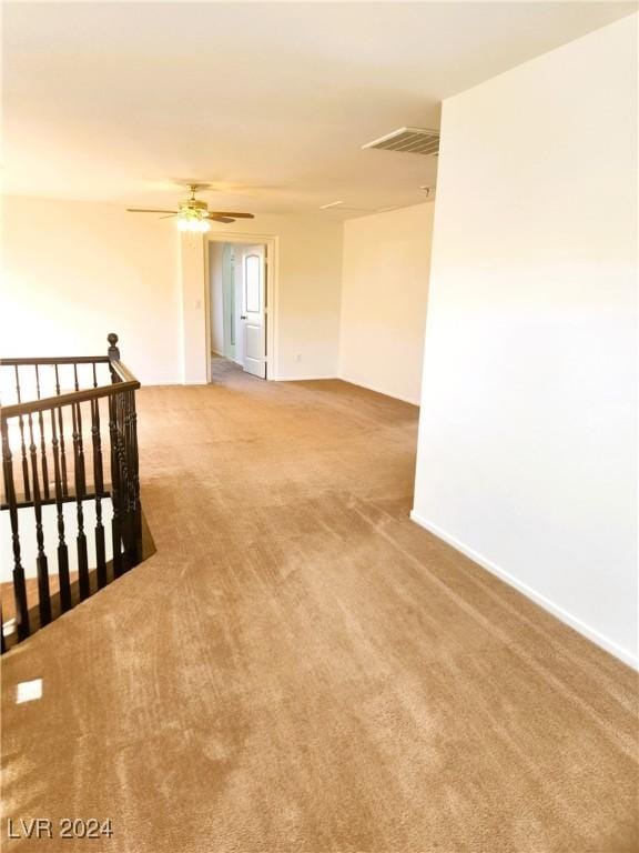 spare room with carpet floors, visible vents, and a ceiling fan