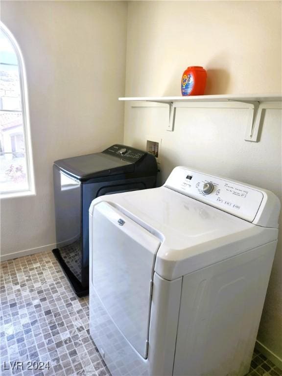 clothes washing area featuring laundry area, brick floor, washing machine and dryer, and baseboards