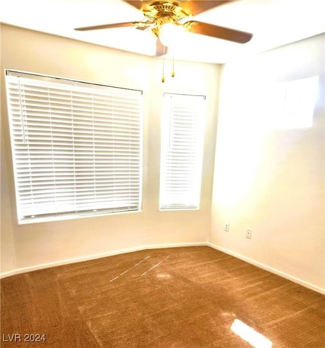 carpeted empty room with ceiling fan and baseboards