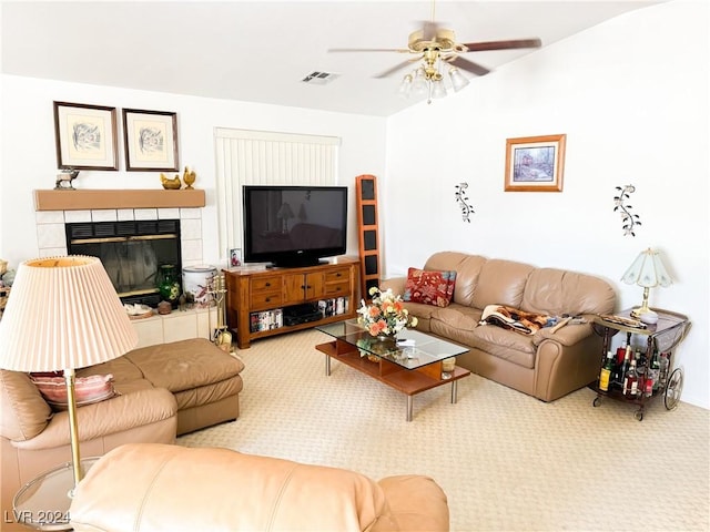 living room featuring ceiling fan, a tiled fireplace, and carpet floors