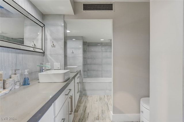 full bathroom with hardwood / wood-style floors, toilet, shower with separate bathtub, and vanity