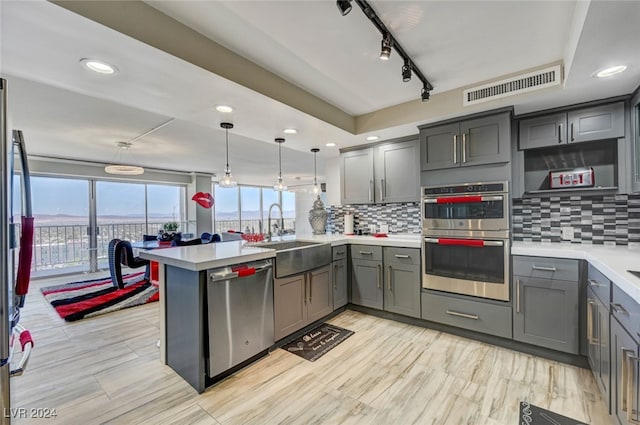 kitchen featuring tasteful backsplash, hanging light fixtures, stainless steel appliances, sink, and kitchen peninsula