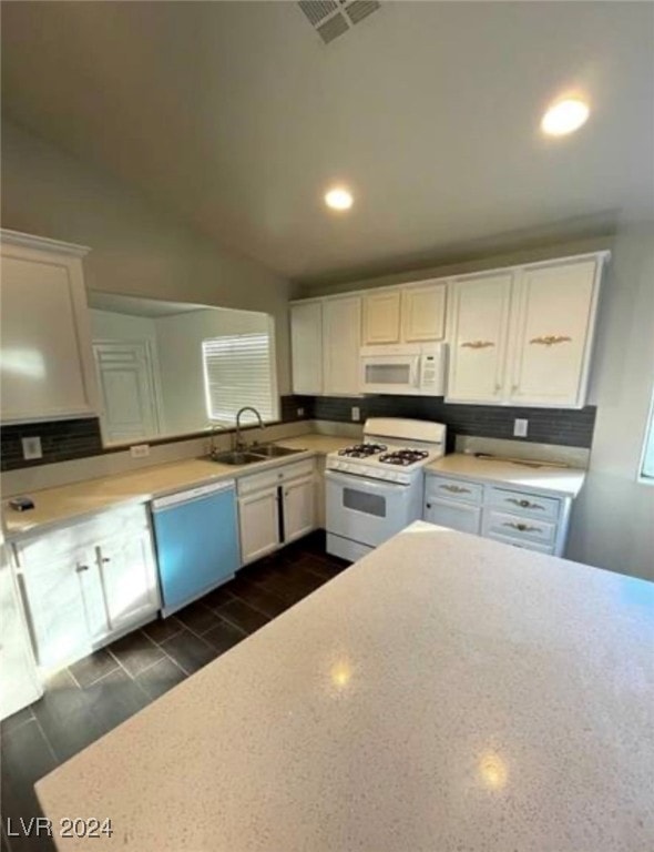 kitchen featuring sink, white appliances, vaulted ceiling, and white cabinetry