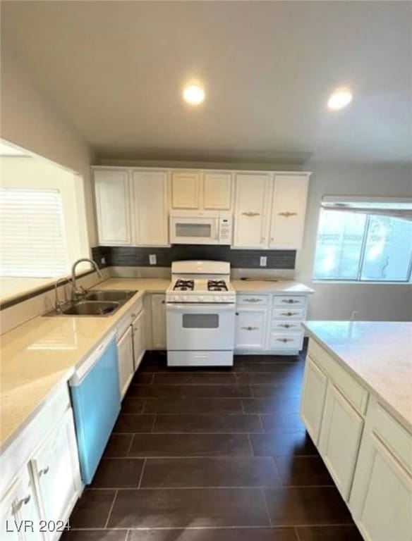 kitchen with sink, light stone counters, white appliances, and white cabinets