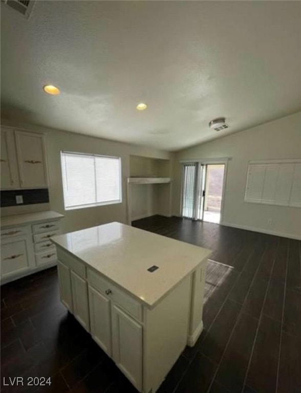 kitchen with white cabinetry, vaulted ceiling, dark hardwood / wood-style flooring, and a kitchen island