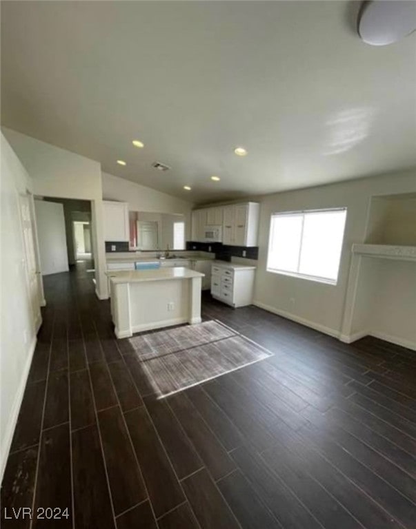 kitchen featuring dark hardwood / wood-style floors, vaulted ceiling, a kitchen island, and white cabinets