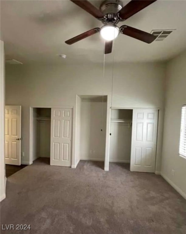 unfurnished bedroom featuring carpet floors, ceiling fan, and two closets