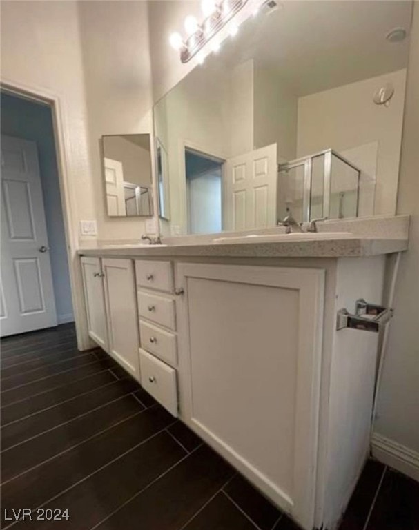 bathroom featuring hardwood / wood-style flooring, double sink vanity, and an enclosed shower