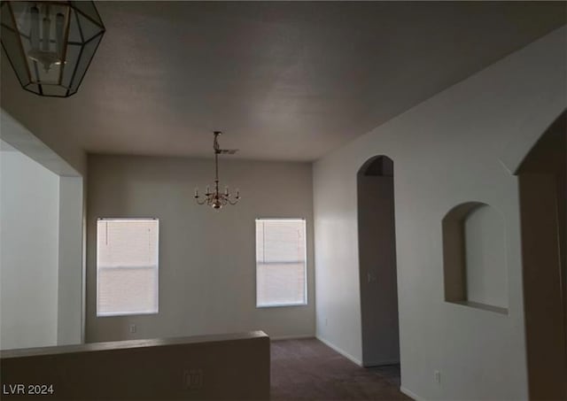 unfurnished dining area featuring carpet and a chandelier