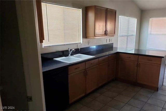 kitchen featuring light tile patterned floors, lofted ceiling, sink, and dishwasher