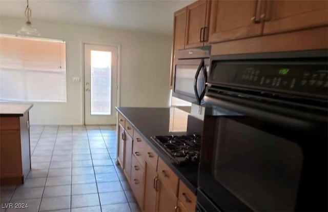 kitchen featuring light tile patterned floors, black appliances, and hanging light fixtures